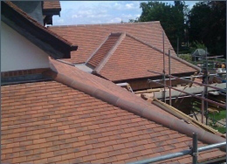 Clay tile roof being laid, with scaffolding
